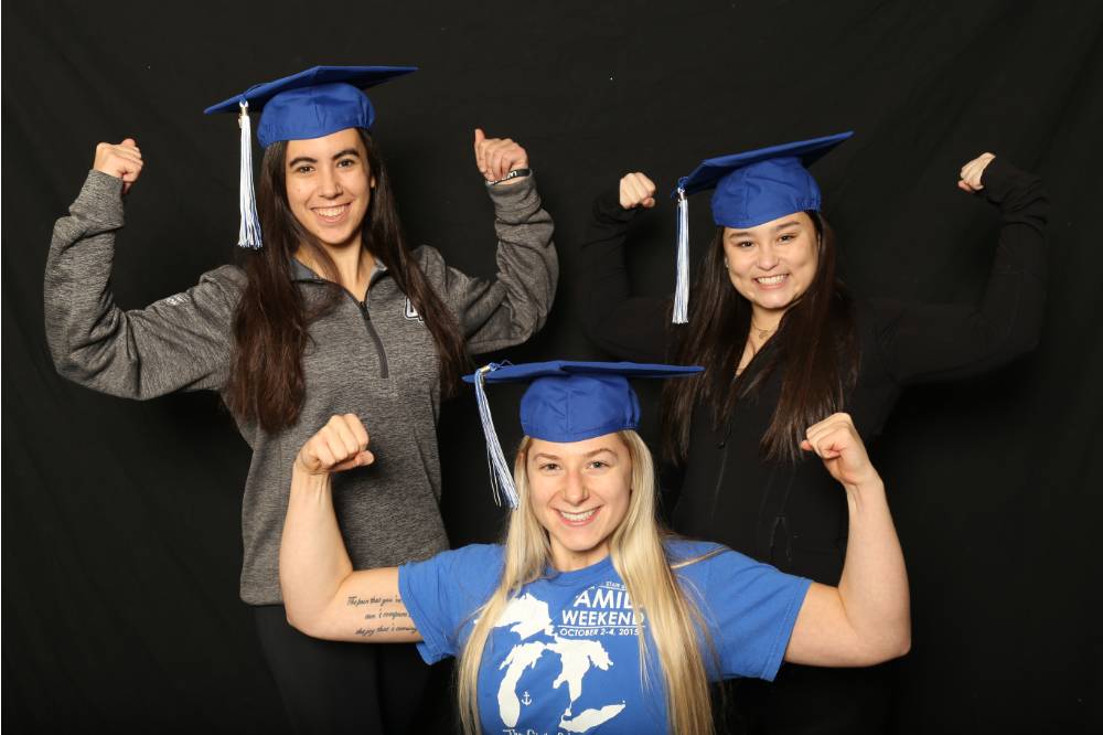 three students doing muscle signs